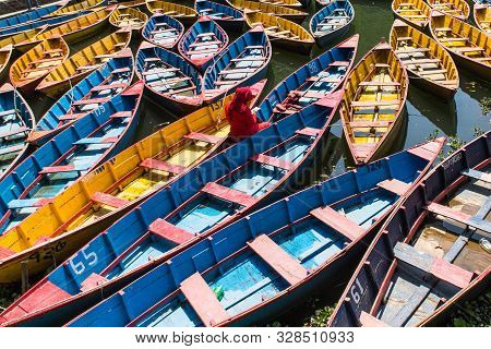 Colorful Boats In Fewa Lake In Pokhara, Nepal With Women In Red Sitting Inside