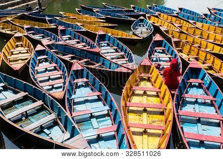 Colorful Boats In Fewa Lake In Pokhara, Nepal With Women In Red Sitting Inside