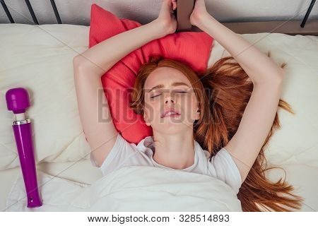 Redhaired Ginger Female Person Lying On A Bed With Pink Pillows Eyes Closed From Pleasure Next To Th