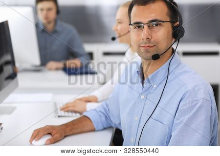 Call Center. Group Of Casual Dressed Operators At Work. Focus On Adult Businessman In Headset At Cus