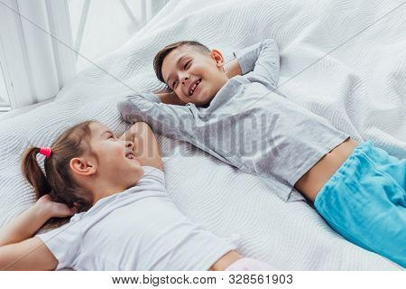Two Sweet Kids Lying On Cozy Couch, Hands Over Head, Ready To Take A Nap.
