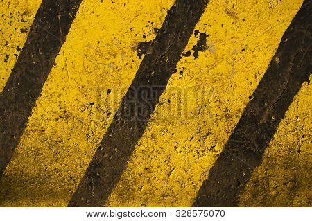 Textured Concrete Slab Painted In Yellow And Black Stripes.