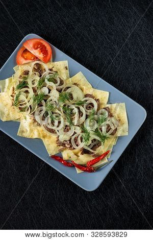 Beshbarmak Is A National Kazakh Dish - Square Pasta With Boiled Meat And Onions. On A Black Backgrou