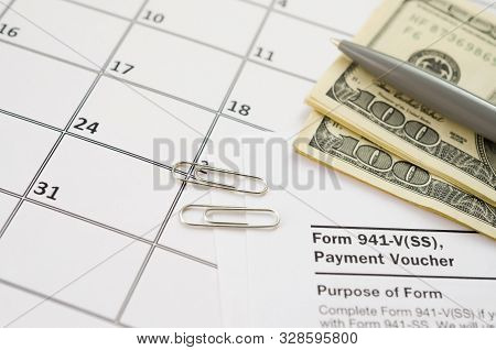 Irs Form 941-v Payment Voucher Blank Lies With Pen And Many Hundred Dollar Bills On Calendar Page