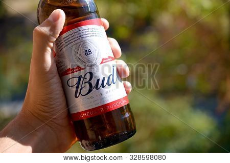 Kharkov, Ukraine - September 23, 2019: Bottle Of Budweiser Bud Beer In Male Hand On A Green Trees Ba