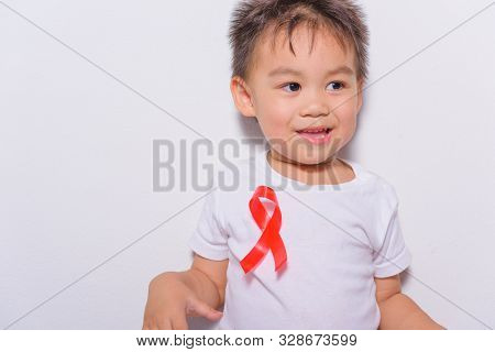 Closeup Of Boy Kid With Red Ribbon Support Hiv Aids On Shirt, World Aids Day And Medicine Concept Wi