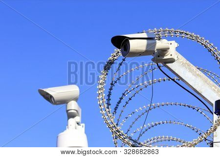 Territory Perimeter Security. Barbed Wire Fence And Camera Protect Against Intruders.
