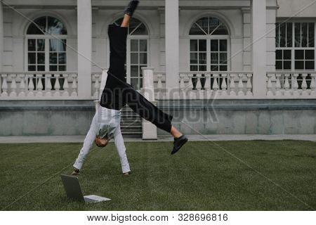 Successful businessman turn handsprings next to her laptop. City businesswoman working.