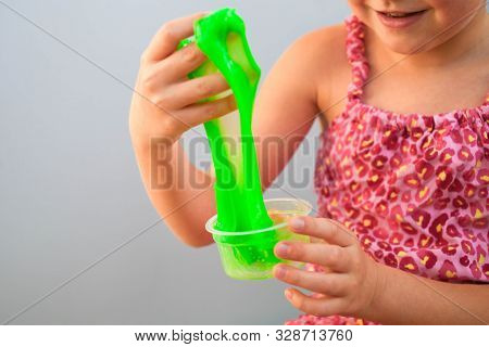 Kid Squeeze And Stretching Toy Slime. Cute Little Girl Is Played By Green Slime
