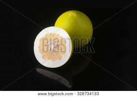 One Pomelo And Half Sliced Pomelo Fruit On Black Background With Reflection