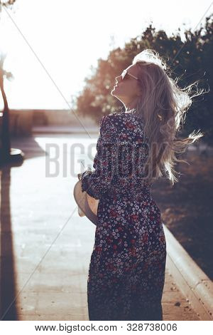 Carefree Blone Woman Posing At City Park Sunset, Floral Pattern Dress