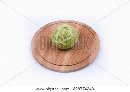One Green Kohlrabe Cabbage Lies On A Wooden, Round Board, White Background
