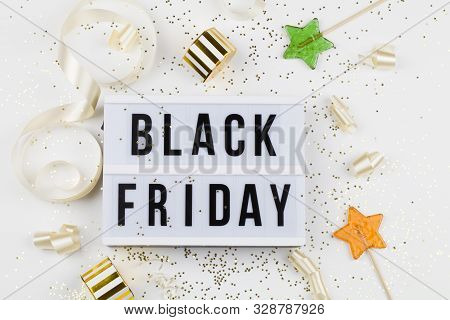 Black Friday Sale Text On White Lightbox, Golden Stars, Holiday Ribbon, Lollipop And Box Around On W