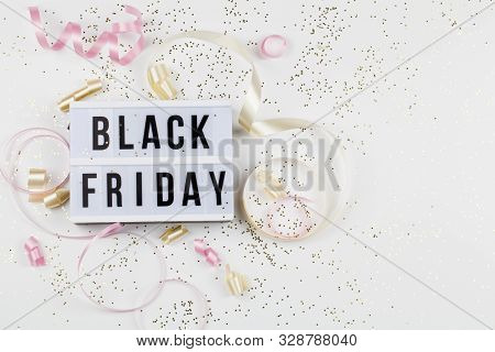 Black Friday Sale Text On White Lightbox, Golden Stars And Holiday Ribbon Around On White Background