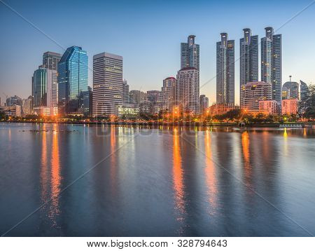 Lake In City Park Under Skyscrapers At Twilight. Benjakiti Park In Bangkok, Thailand