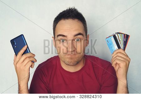 Guy Chooses A Credit Card To Pay. Bewilderment On The Mans Face When Paying Through A Mobile Phone. 