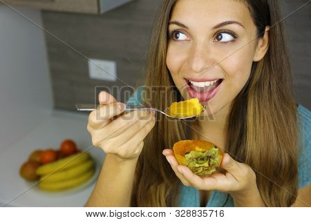 Healthy Woman Eating Persimmon Kaki Fruit At Home. Close Up From Above Looking To The Side.