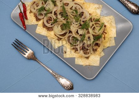 Beshbarmak Is A National Kazakh Dish - Square Pasta With Boiled Meat And Onions. On A Blue Backgroun