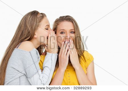 Blondine studerende hviske at veninden stummes mod hvid baggrund