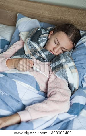 Student Is Lying At Home In Bed With Flu Symptoms. A Girl In Kravata With High Temperature