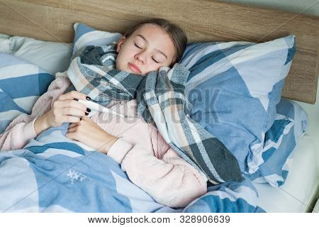 Student Is Lying At Home In Bed With Flu Symptoms. A Girl In Kravata With High Temperature