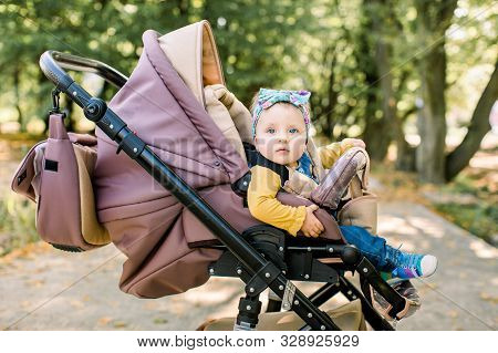 Cute Little Beautiful Baby Girl Sitting In The Pram Or Stroller And Waiting For Mom. Happy Smiling C