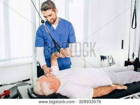 Kinesiologist Doing Therapeutic Exercises For An Elderly Patient. Kinesitherapy At The Medical Cente
