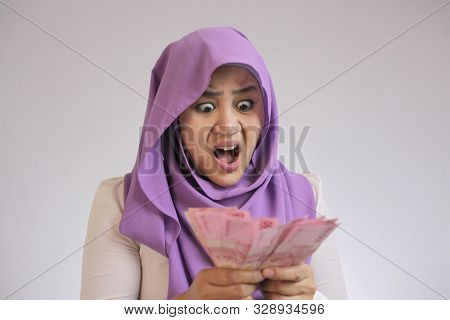 Portrait Of Young Asian Muslim Woman Shocked When Counting Her Rupiah Money, Economic Failure Or Ban