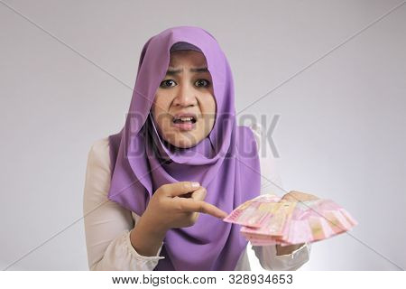 Portrait Of Indonesian Muslim Woman Looked Confused With Her Rupiah Money, Complaining Too Small Sal