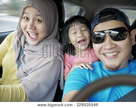 Portrait Of Happy Asian Muslim Family In Mudik Trip, Smiling And Taking Selfie Photo In Car. Mudik I