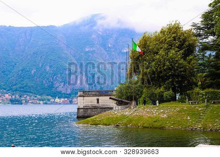 Italian Flag Near Gun With Alps In Background, Lake Como In Mandello Del Lario.