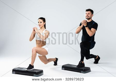 Athletic Couple Doing Exercises Over Steps In Aerobic Class Isolated On White Background. Sport And