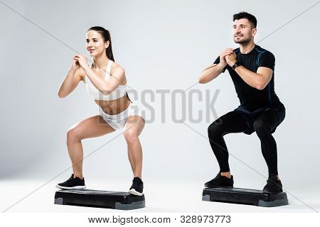 Athletic Couple Doing Exercises Over Steps In Aerobic Class Isolated On White Background. Sport And
