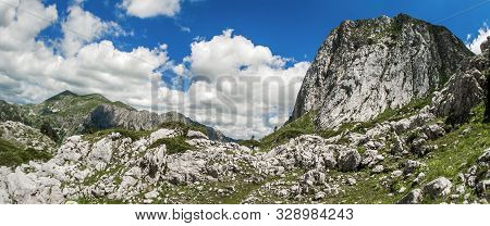 Hikers Walking On Trail. Group Of People Hiking In Mountains With Blooming Meadows And Mountain Peak