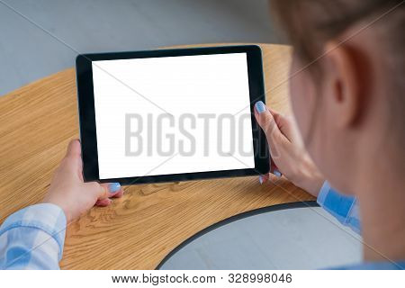 Woman Sitting At Wooden Table And Looking At Black Digital Tablet Computer Device With White Blank S