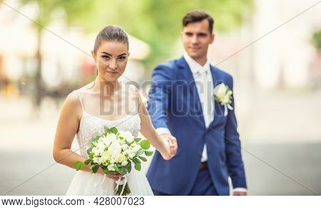 Charming Couple Holding Eeach Others Hand While Wanking In The Town. They Are Wearing Wedding Robes 