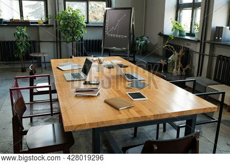 Large table with business objects and group of chairs around it in classroom