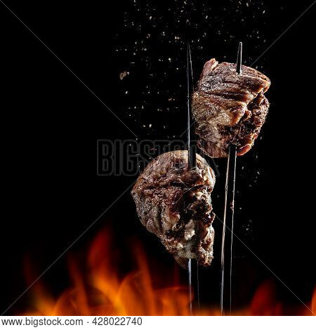 Fork With Pieces Of Delicious Barbecued Meat On Black Background. Delicious Pork Pieces On Rotating 