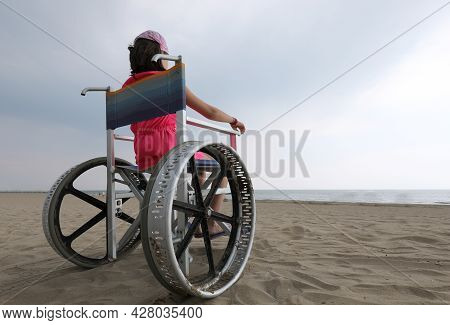 Young Girl In The Wheelchair On The Beach By The Sea And The Special Wheels To Move Smoothly On The 