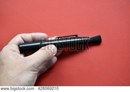 Brush For Cleaning Optics On A Red Background