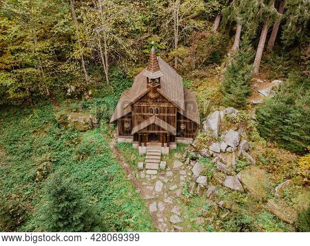 Wooden Pilgrimage Rural Chapel Of Virgin Mary, Cz: Stozecka Kaple And Iron Cross Standing In Forest 