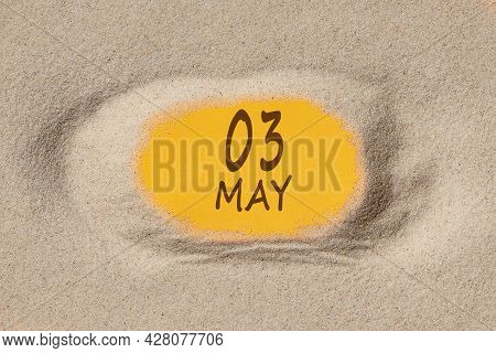 May 3. 3th Day Of The Month, Calendar Date. Hole In Sand. Yellow Background Is Visible Through Hole.