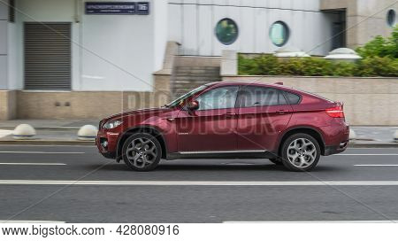 Moscow, Russia - July 2021: Side View Rolling Shot With Red Car In Motion. Bmw X6 E71 Driving Along 