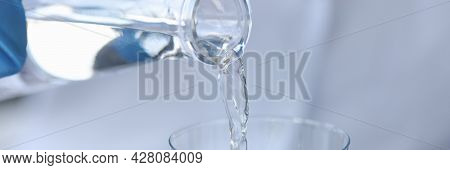 Pure Water Is Poured From A Bottle Into Transparent Glass
