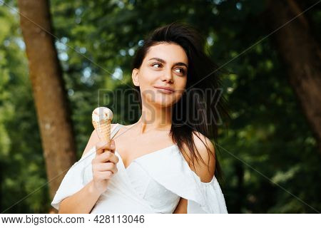 Portrait Of A Beautiful Young Idian Woman Relaxing Outside Eating Ice Cream In The Park And Looking 