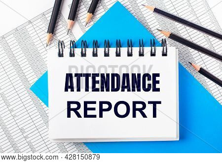 White Notebook With The Text Attendance Report On The Table Next To Black Pencils On A Blue Backgrou