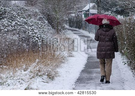 Frau mit Regenschirm ist auf einem FuÃŸweg schlendern.