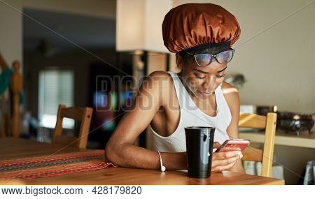 african american woman wearing showercap looking at smartphone during morning routine