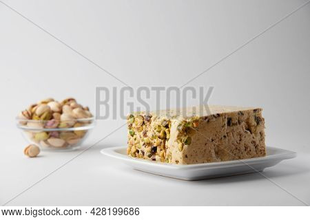 Organic Halva With Pistachios On A White Plate Isolated On White. Traditional Middle Eastern Sweets.