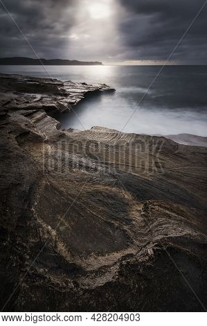 Light Pouring Down Onto The Rocks And The Ocean On The Coast